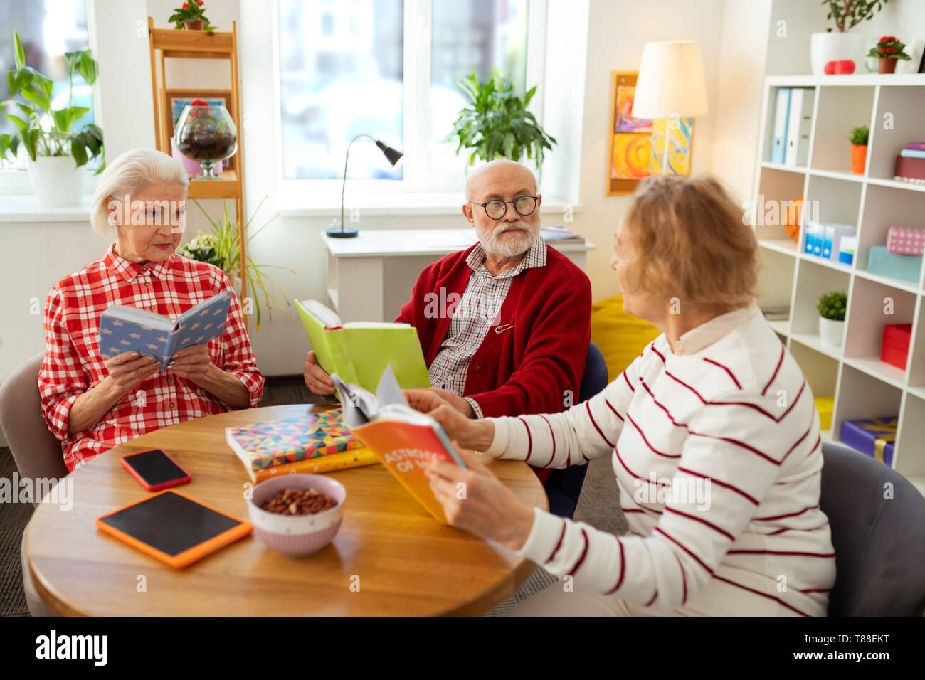 Bonito pueblo senior hablando de diferentes libros Foto de stock
