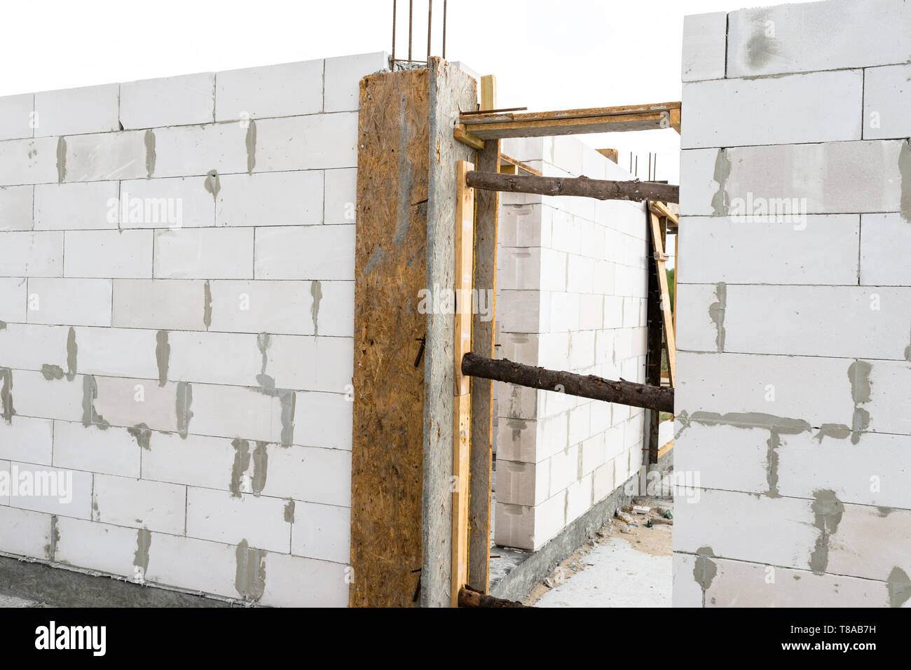 Las paredes de una casa construida de ladrillo blanco con pilares de hormigón armado al final de la cual hay varillas acanaladas, encofrados de madera visibles desde el Foto de stock