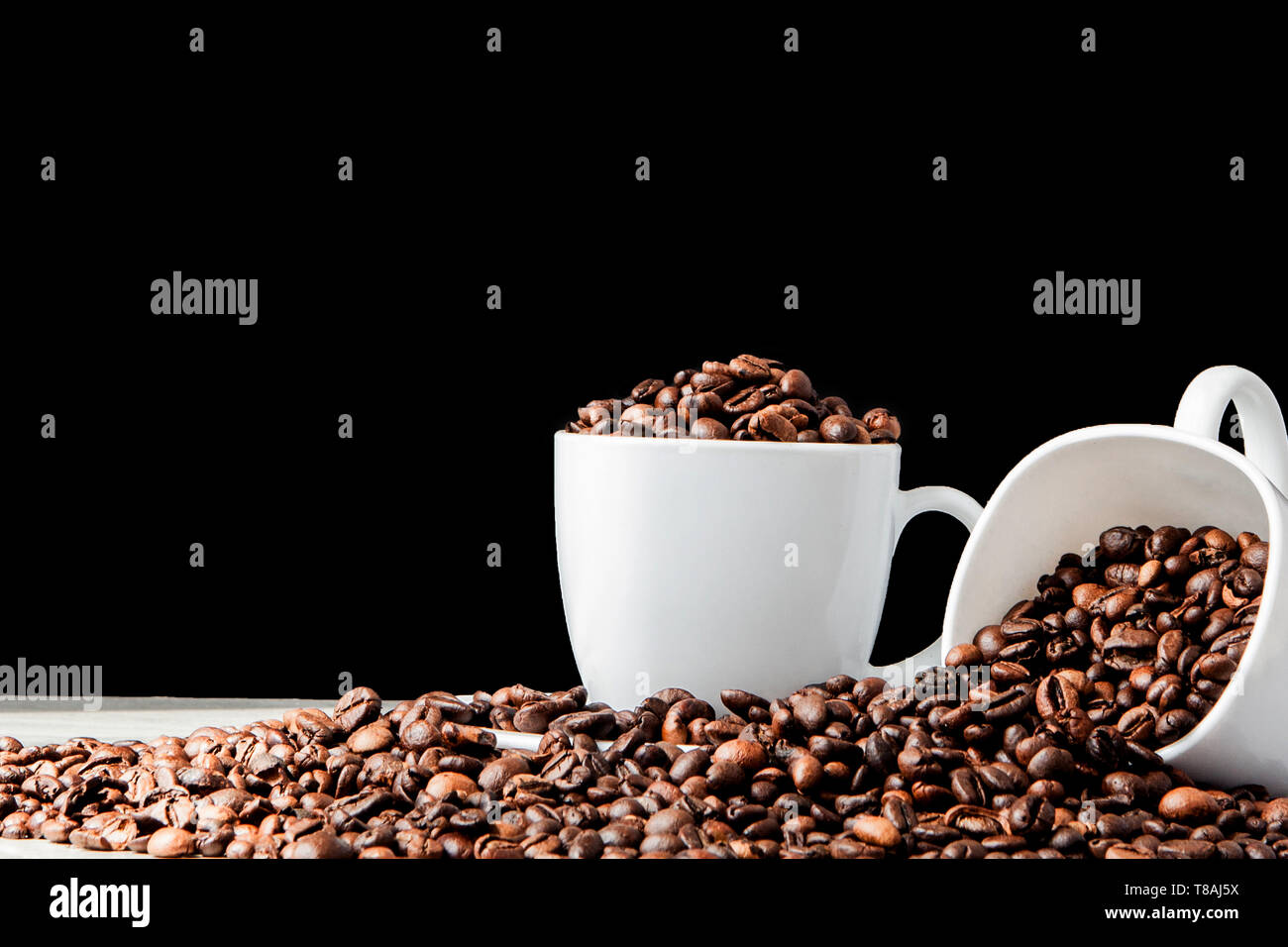 Café Negro en taza blanca y granos de café sobre fondo negro. Vista superior, espacio para el texto Foto de stock