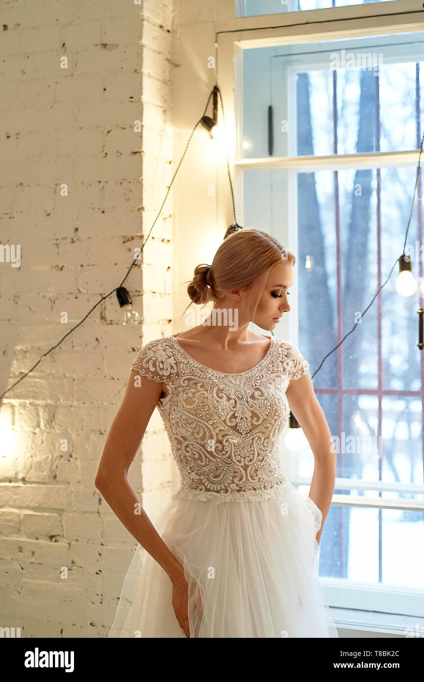 La novia en un blanco vestido encaje bordado con canesú, interiores en  estilo loft.High Key Fotografía de stock - Alamy