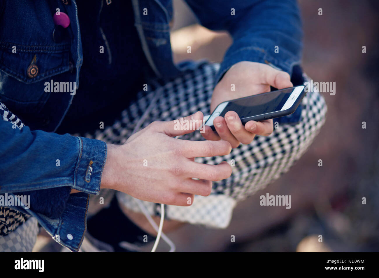 Moda vestidos adolescente sentado y sosteniendo un teléfono táctil, que se comunica en la red social Foto de stock
