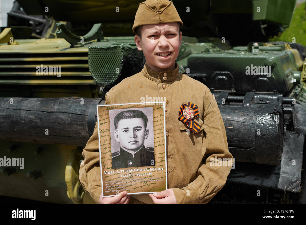 Muchacho vestido con uniforme militar soviético durante la segunda guerra  mundial posando cerca del tanque del ejército y mantiene el retrato de su  abuelo, que luchó y fue una guerra h Fotografía