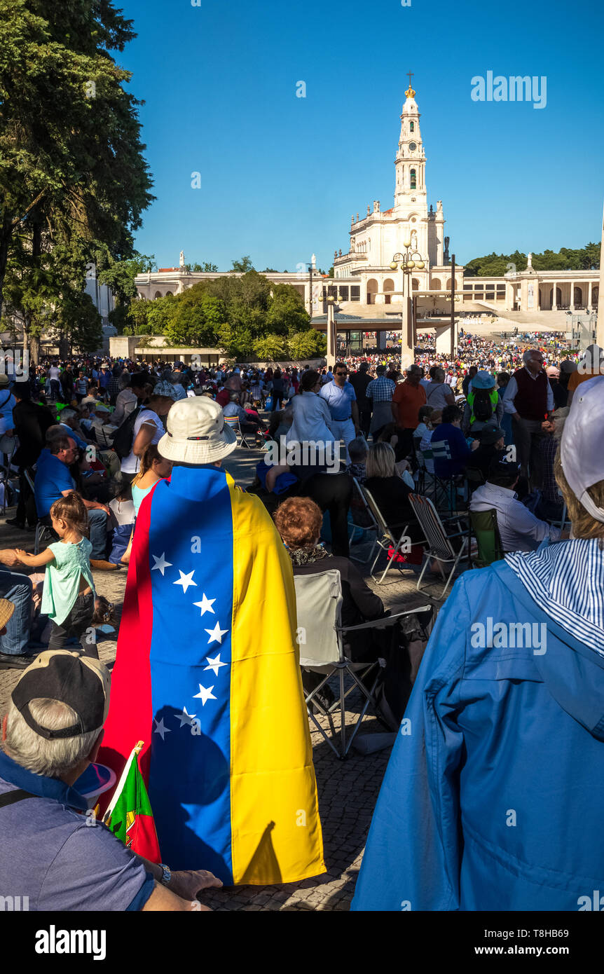 Fátima, Portugal - 12 de mayo de 2019: Mujer con la bandera de Venezuela detrás de su espalda en el Santuario de Fátima, Portugal. Foto de stock