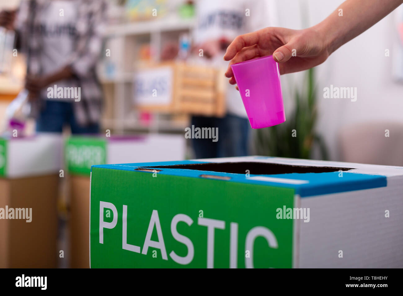 Chica colocando cristal rosado en el cuadro de clasificación de los residuos de plástico Foto de stock