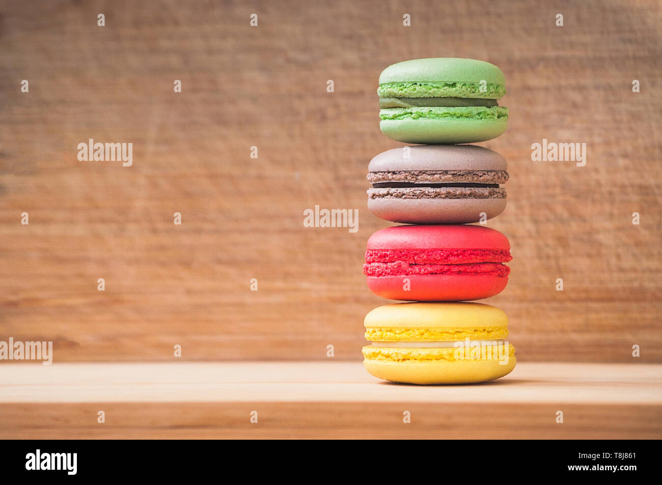Cuatro coloridos sabrosos macarons franceses aislado sobre la textura de la madera Foto de stock