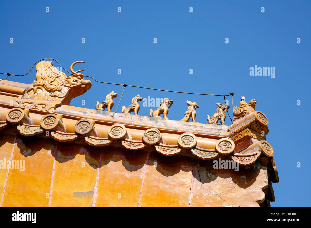 El techo del templo tradicional chino con azulejos de cerámica de color naranja y una piedra roja ornamentado gable Foto de stock