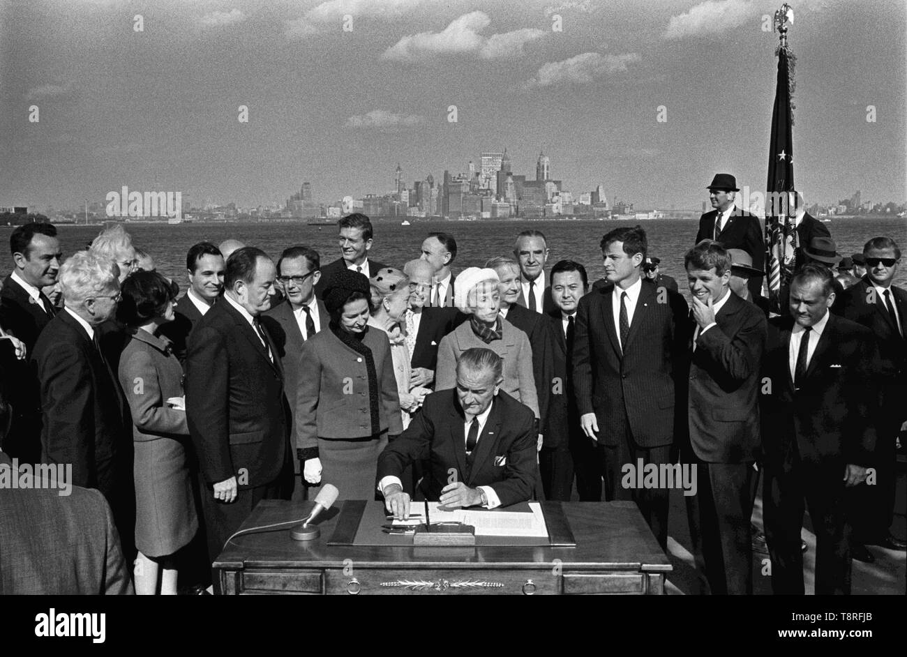 El presidente Lyndon B. Johnson firma la Ley de inmigración como vicepresidente Hubert Humphrey, Lady Bird Johnson, Muriel Humphrey, el Senador Edward (Ted) Kennedy, el Senador Robert F. Kennedy, y otros. Liberty Island, Nueva York, Nueva York - 3 de octubre de 1965 Foto de stock