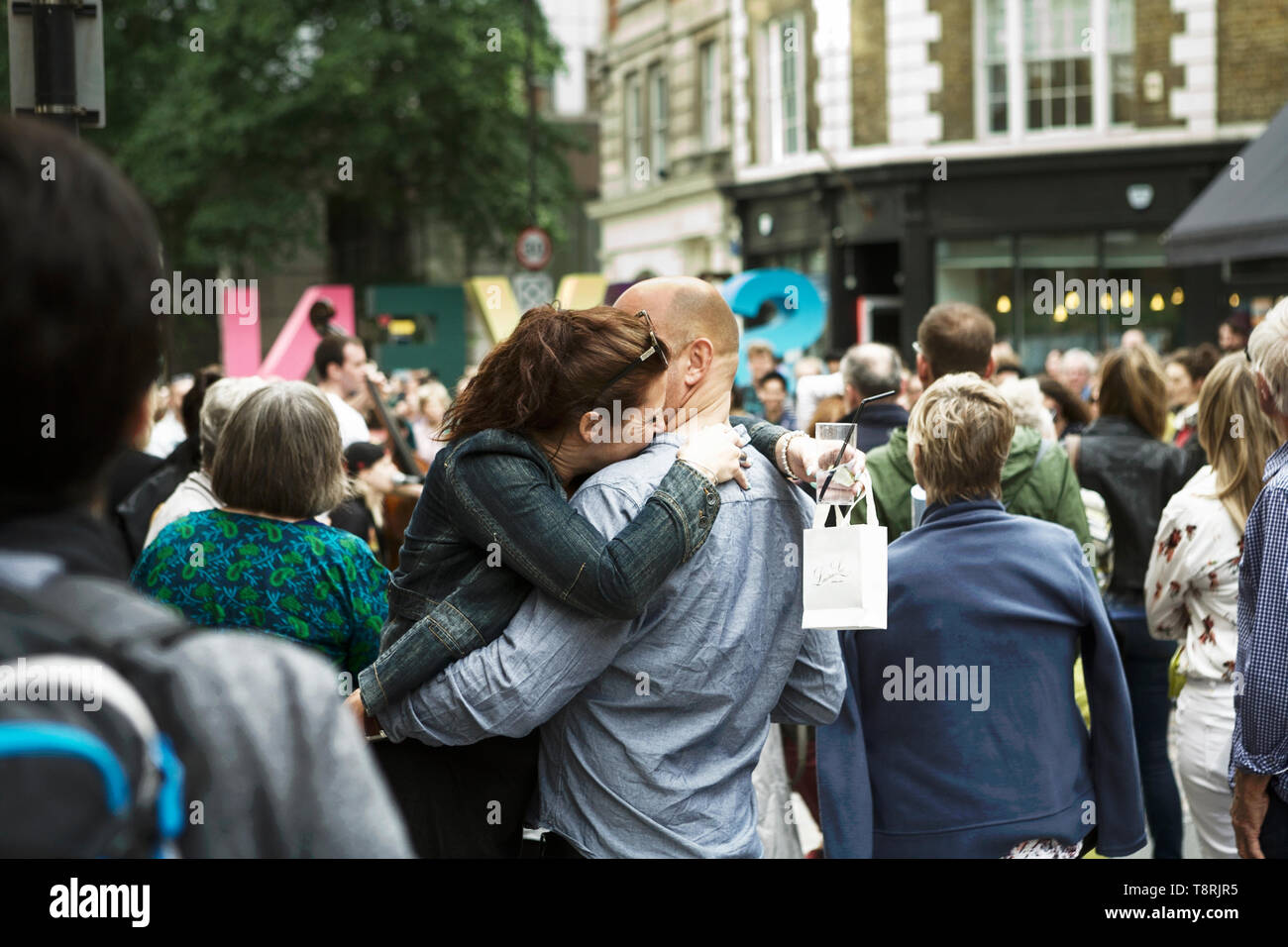 Par afectuoso abrazo en un grupo de personas. El afecto humano. Las emociones humanas. Escena de una calle de Londres. Foto de stock