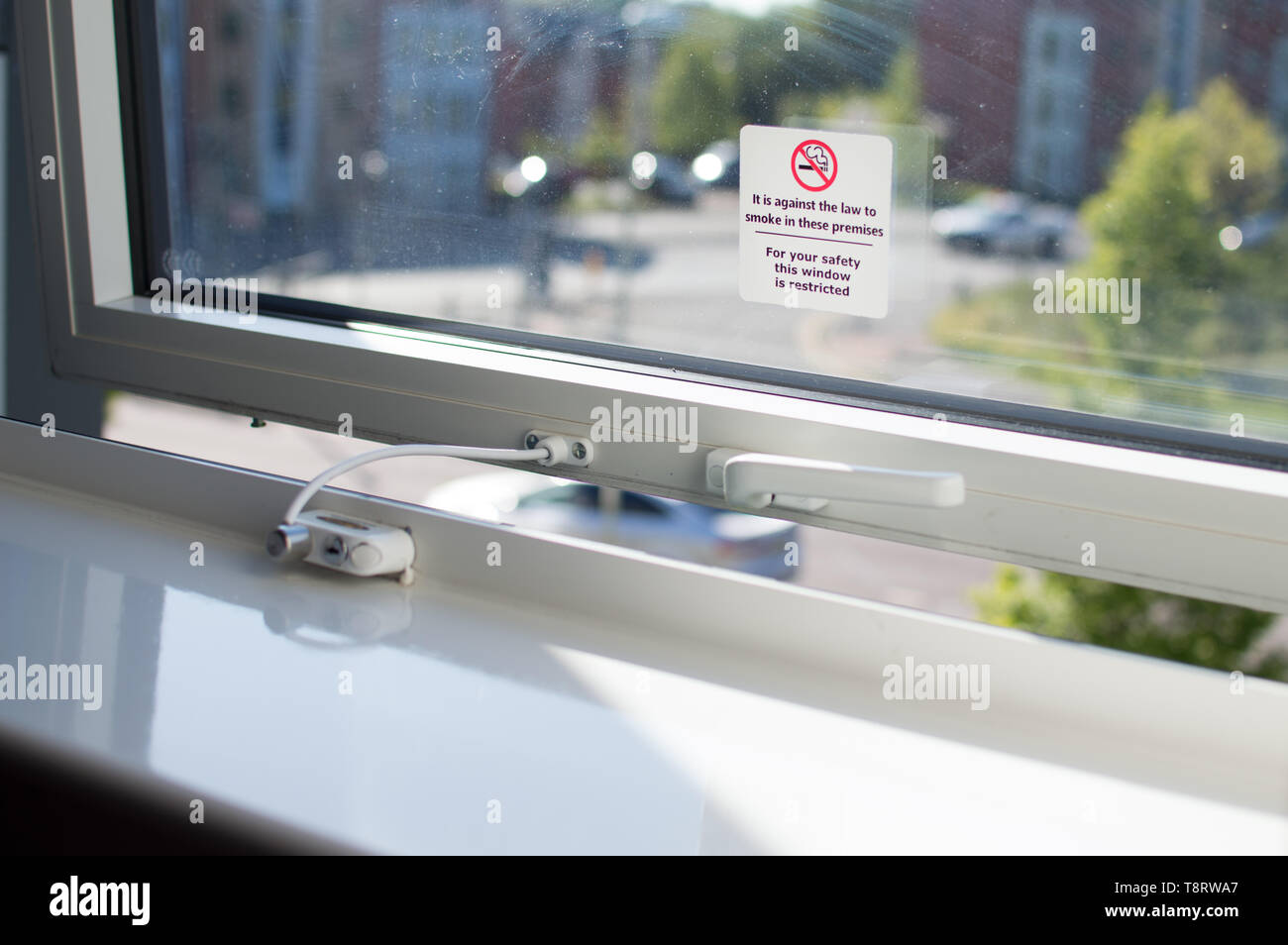 Un signo de no fumar y restricción de la ventana información sobre una ventana de vidrio en una habitación de hotel Foto de stock