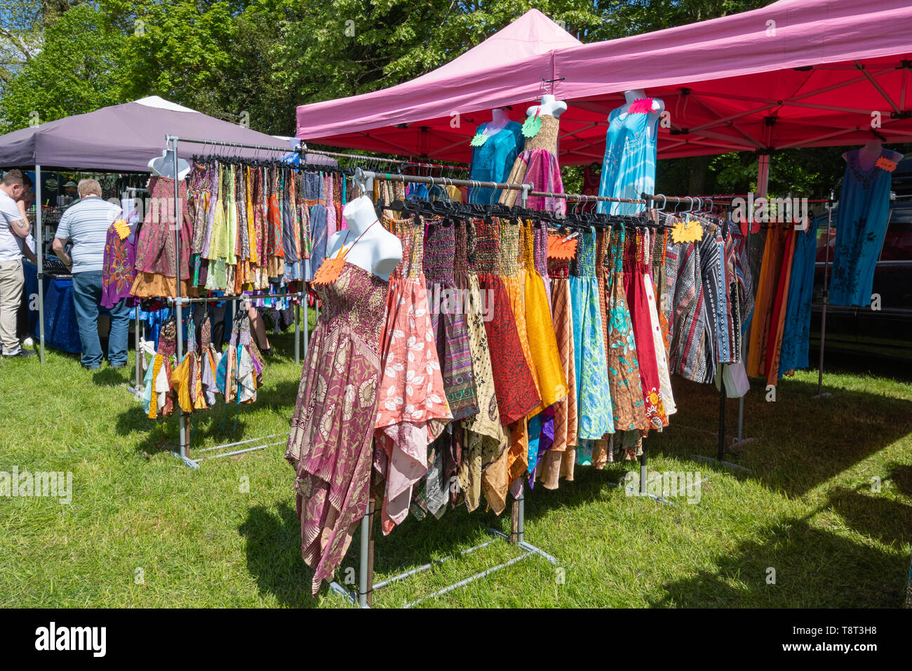 Colorido sol (coloridos vestidos vestidos de verano) a la venta en un puesto en el mercado en un show, UK Foto de stock