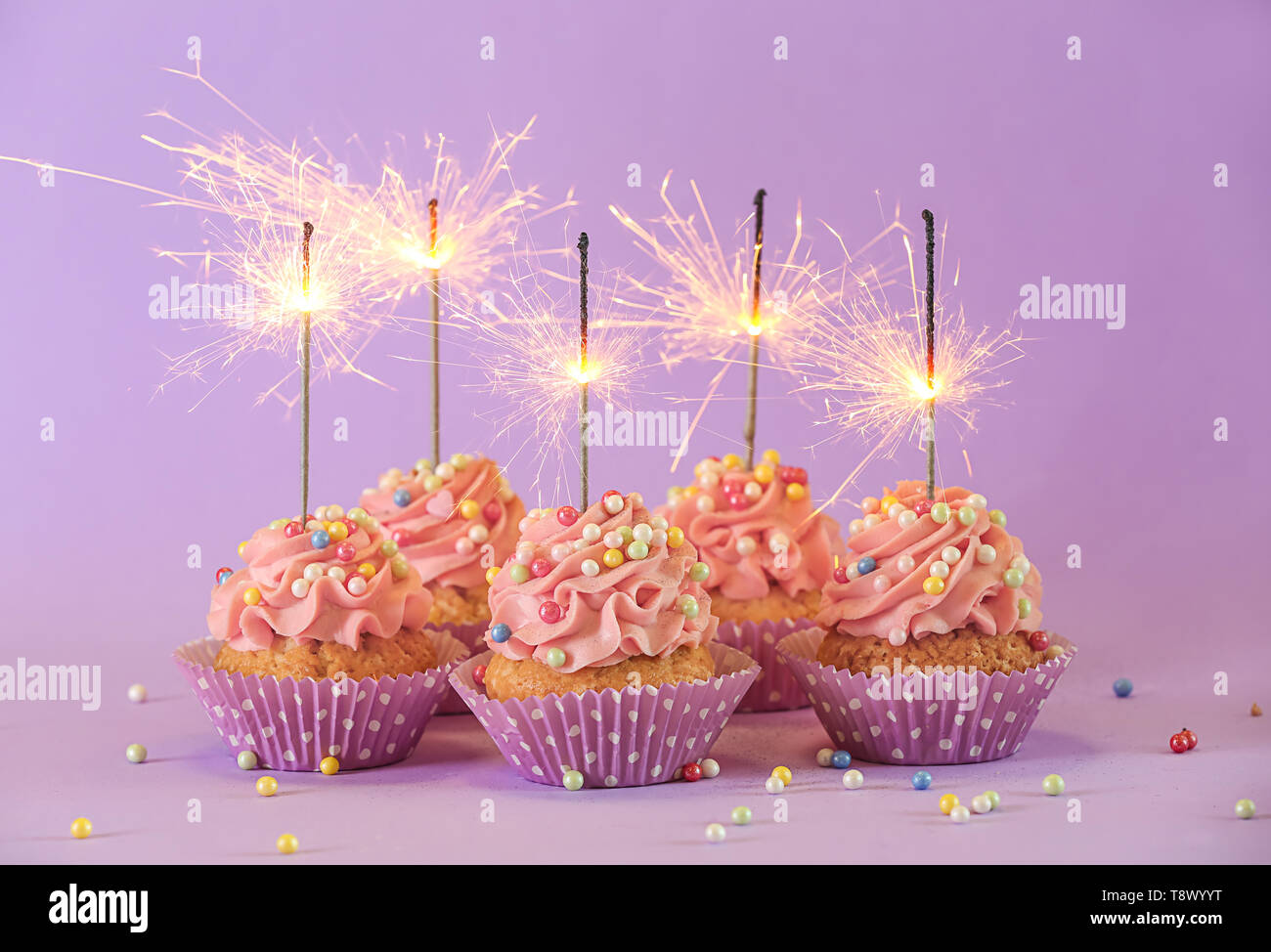 Deliciosos cupcakes de cumpleaños con velas de fuegos artificiales sobre  fondo de color Fotografía de stock - Alamy
