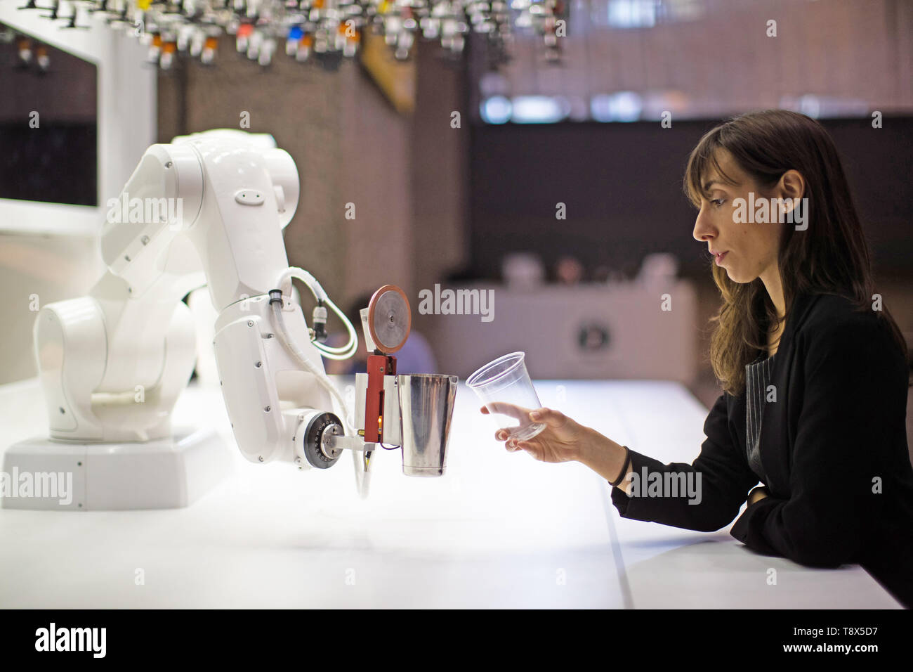 Una mujer interactúa con un camarero robótico llamado 'Makr Shakr' en una rueda de prensa previa para el 'AI: más que humano" exposición en el Barbican Centre de Londres. Los principales nueva exposición explora la relación entre el hombre y la inteligencia artificial. Foto de stock