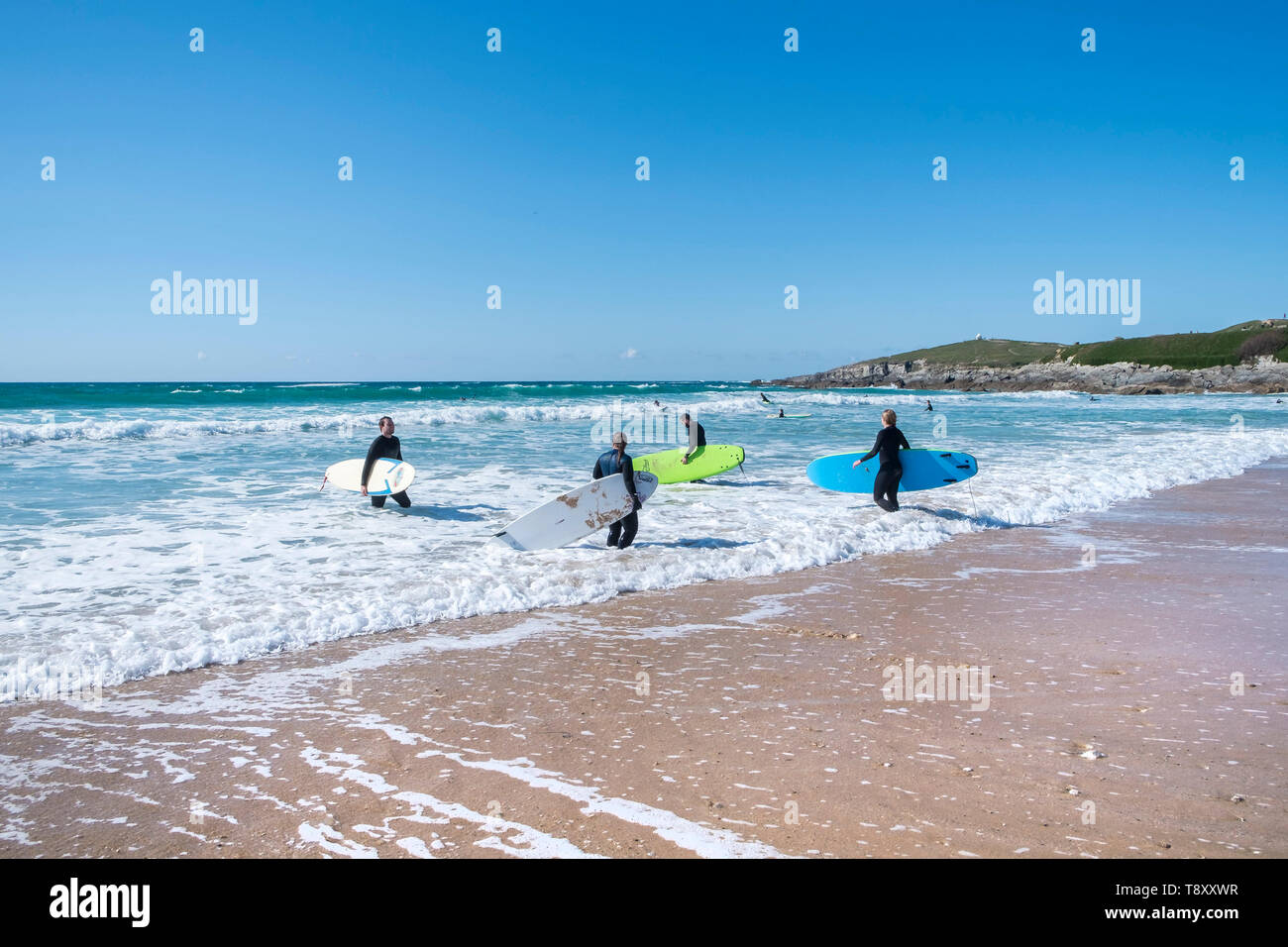 Los surfistas caminando hacia el mar en el surf hotspot Fistral en Newquay en Cornualles. Foto de stock