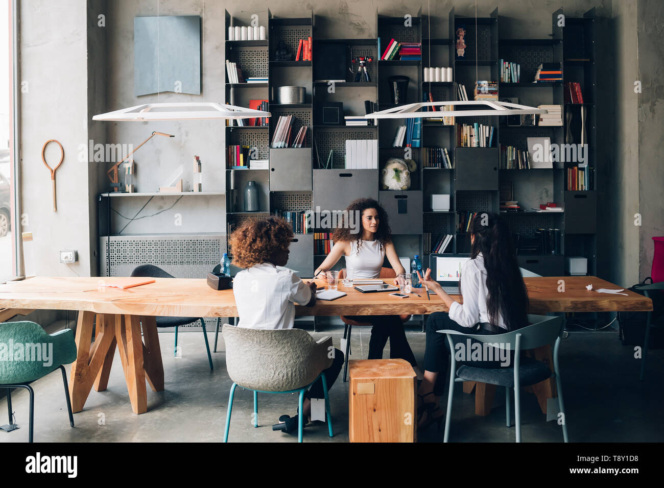 Mujeres jóvenes que tienen reunión en una oficina moderna - ingeniosos, creatividad, interacción Foto de stock