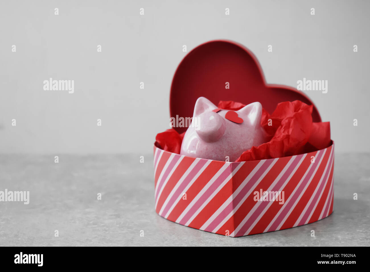Hucha en caja de regalo con forma de corazón sobre fondo gris. Concepto de  la compra de regalos para el día de San Valentín Fotografía de stock - Alamy