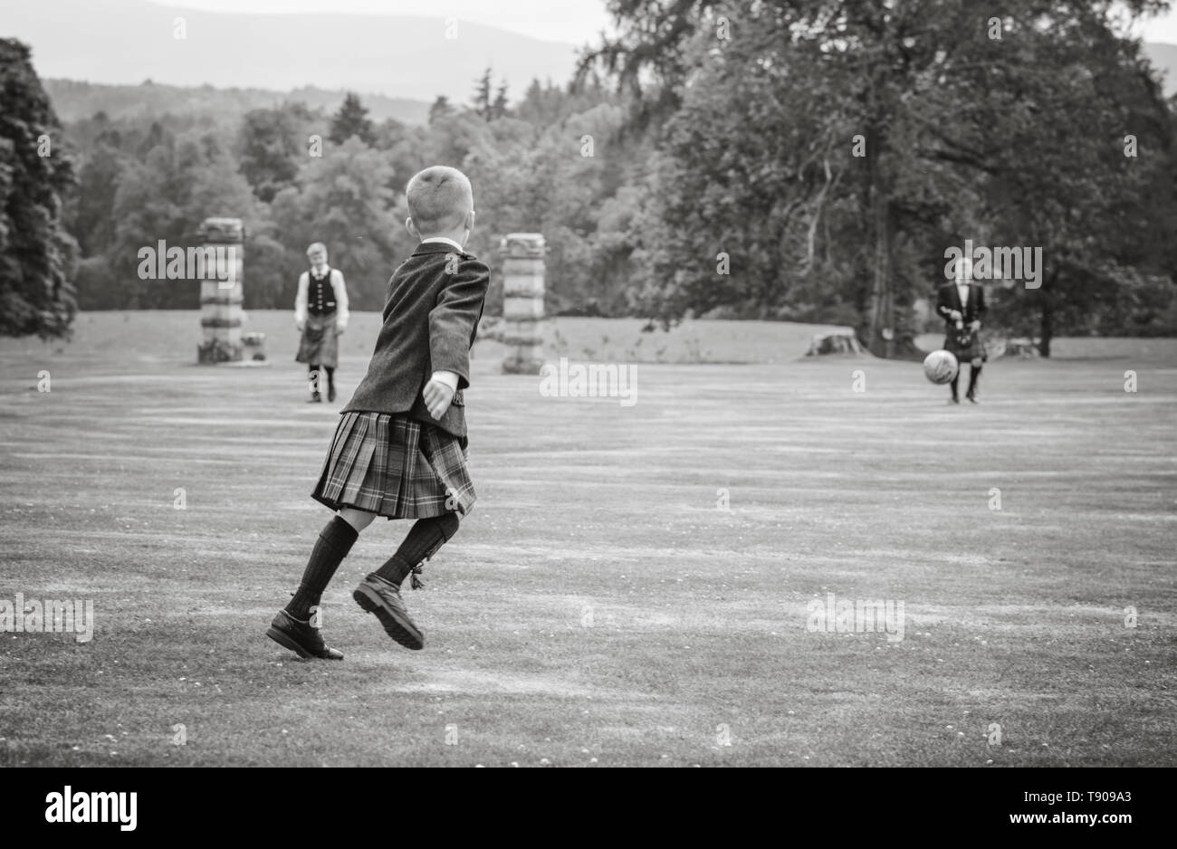 los chicos juegan al fútbol en kilts Foto de stock