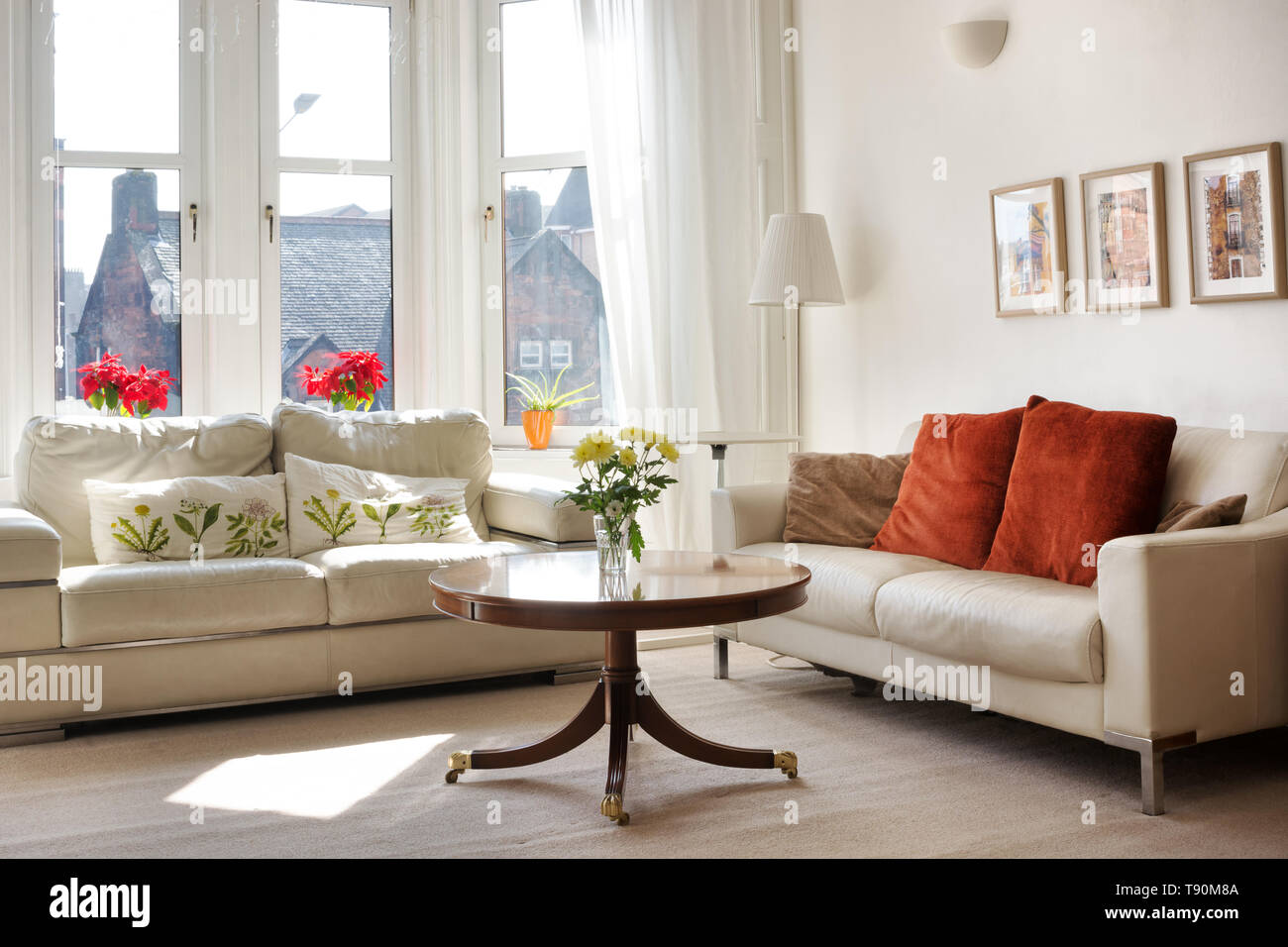 Estilo clásico soleada sala de estar con dos sofás de cuero y una pequeña  mesa redonda Fotografía de stock - Alamy