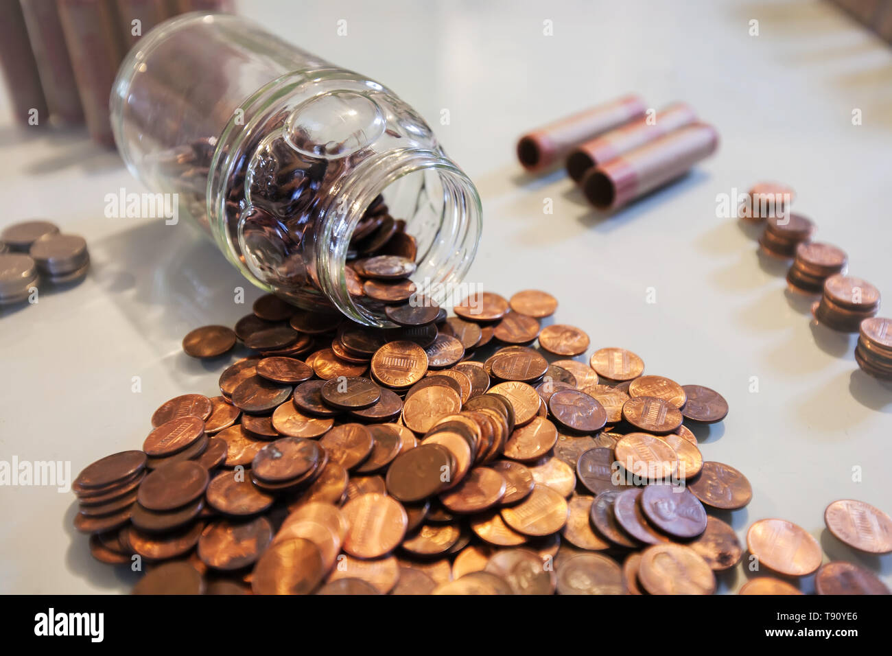 Una jarra de cristal derramado de centavos y monedas de hucha o cambio de repuesto de ahorro. Foto de stock