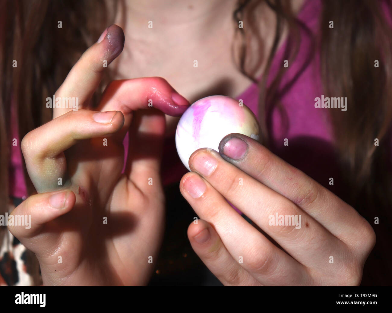 Niña de 13 años mueren de huevos de Pascua, manchando sus manos y dedos en el proceso. Foto de stock