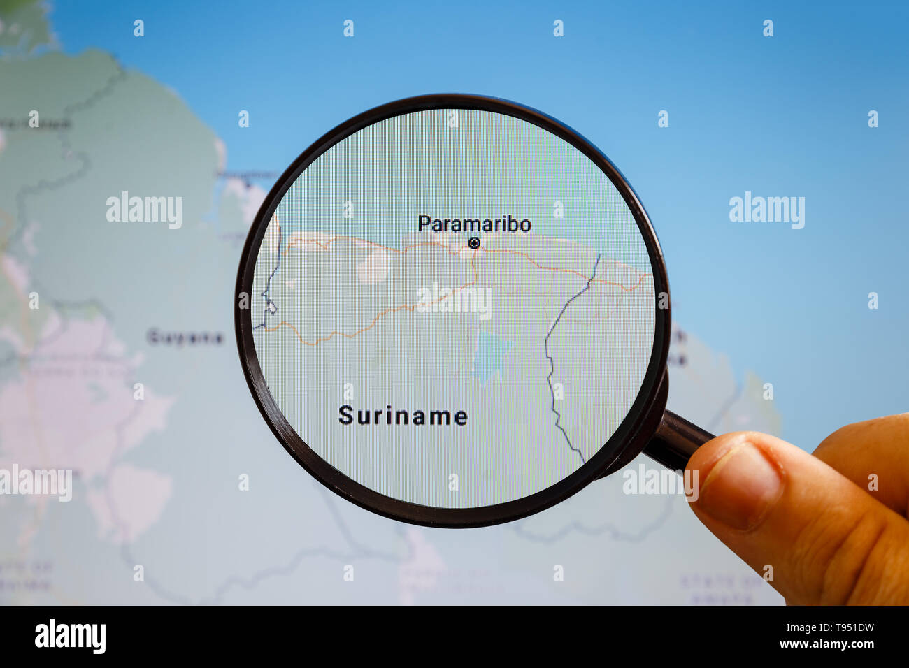 En Paramaribo, Suriname. Mapa político. La ciudad en la pantalla del monitor a través de una lupa en la mano. Foto de stock
