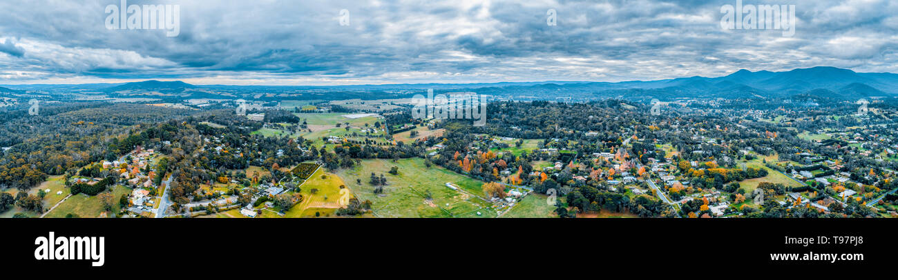 Amplia panorámica aérea del pintoresco paisaje rural con casas rodeada por bosques y montañas. Healesville, Victoria, Australia Foto de stock