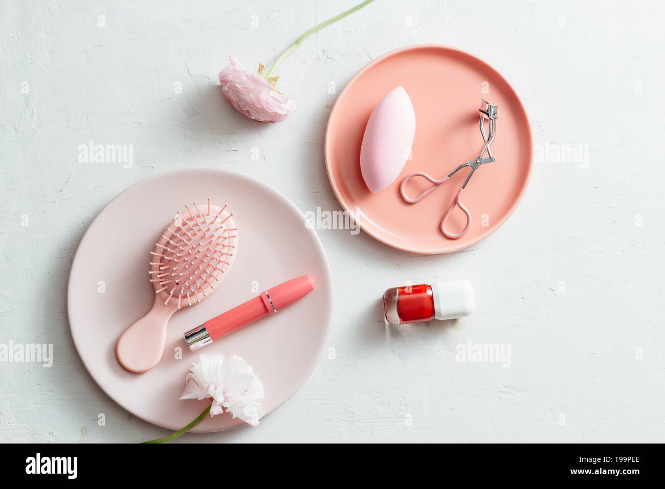 Productos de maquillaje en placa de color rosa sobre fondo blanco. Foto de stock
