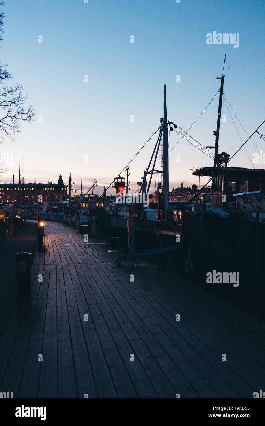 Caminando por un pequeño muelle al atardecer con un montón de pequeños barcos con algunos que tienen las personas que viven en ellos, Estocolmo, Suecia. Foto de stock