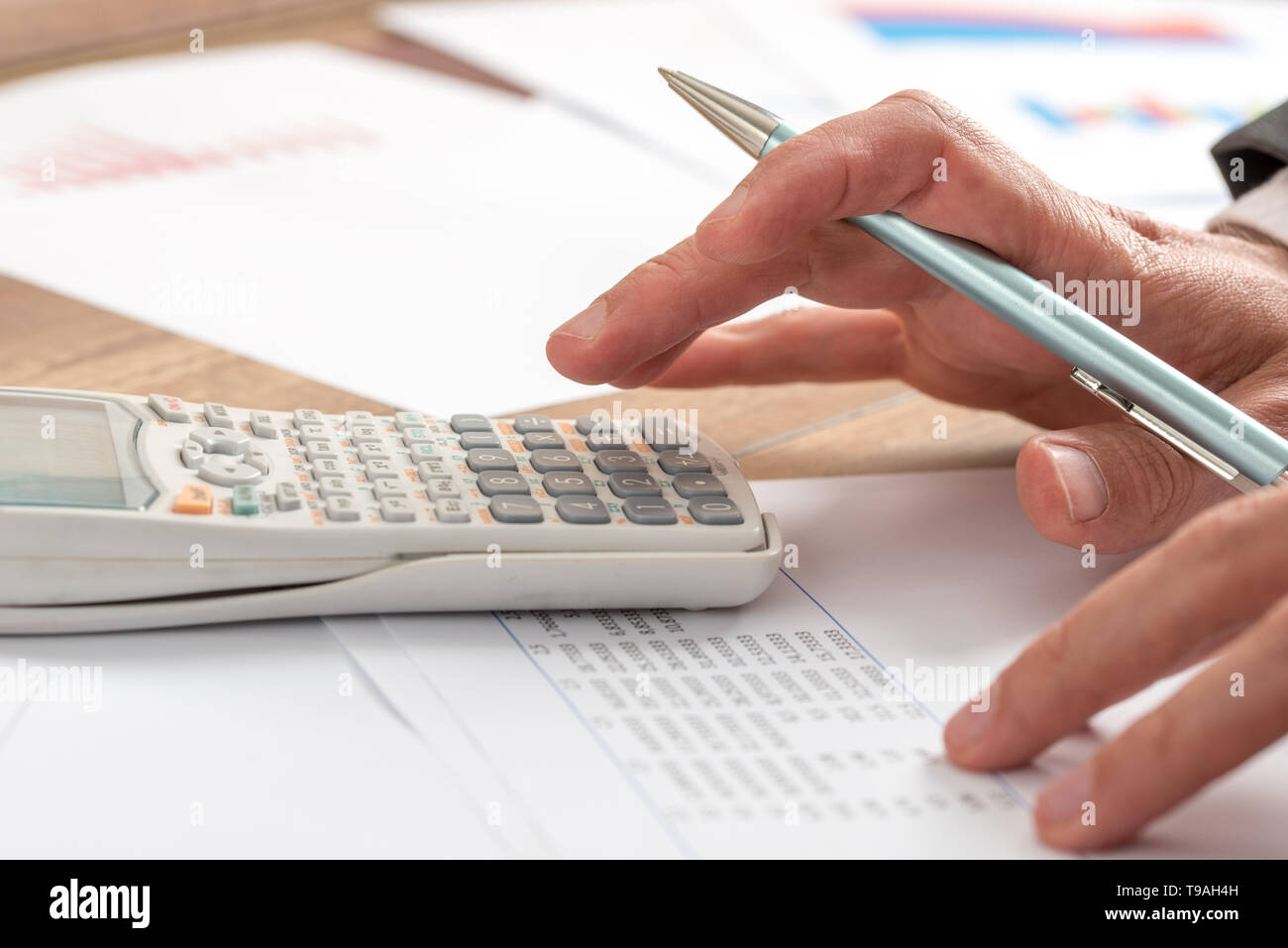 Contador de negocios haciendo un cálculo en un manual de la calculadora en  el escritorio, cerca de su mano sosteniendo un lápiz Fotografía de stock -  Alamy