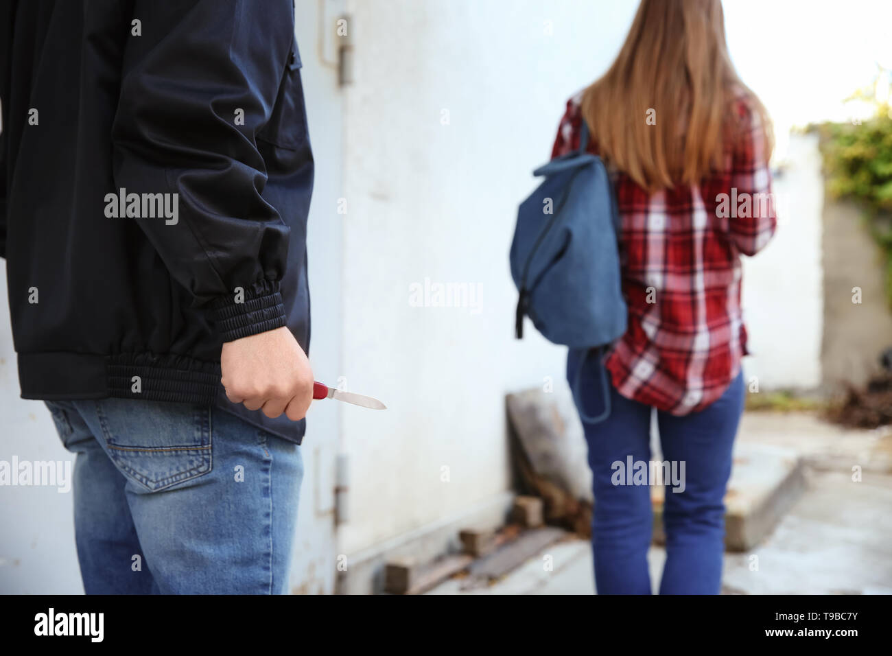 Ladrón masculino con la cuchilla va a robar de mujer al aire libre Foto de stock