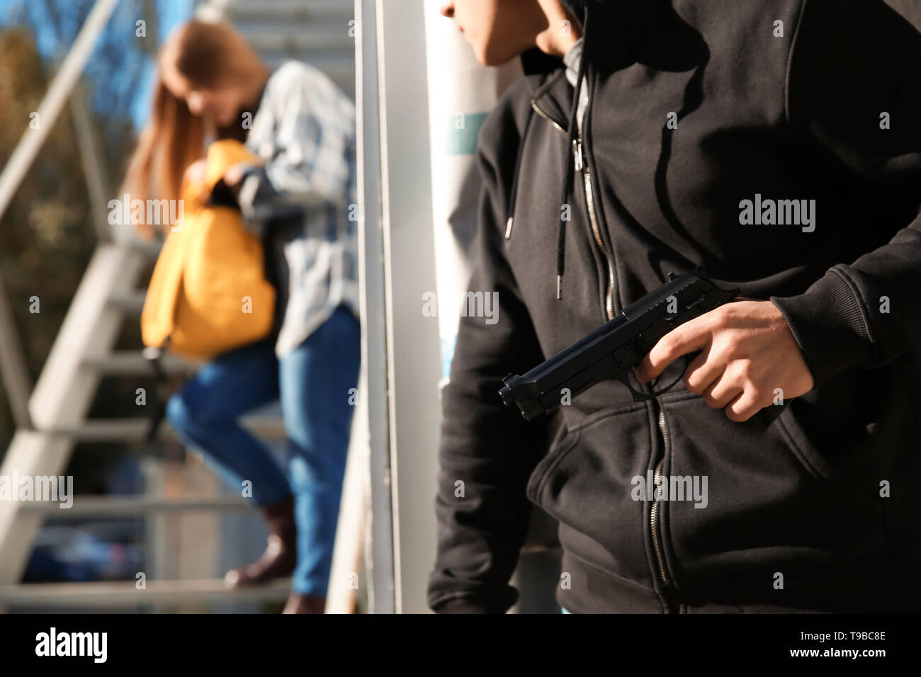 Ladrón macho con pistola va a robar de mujer al aire libre Foto de stock
