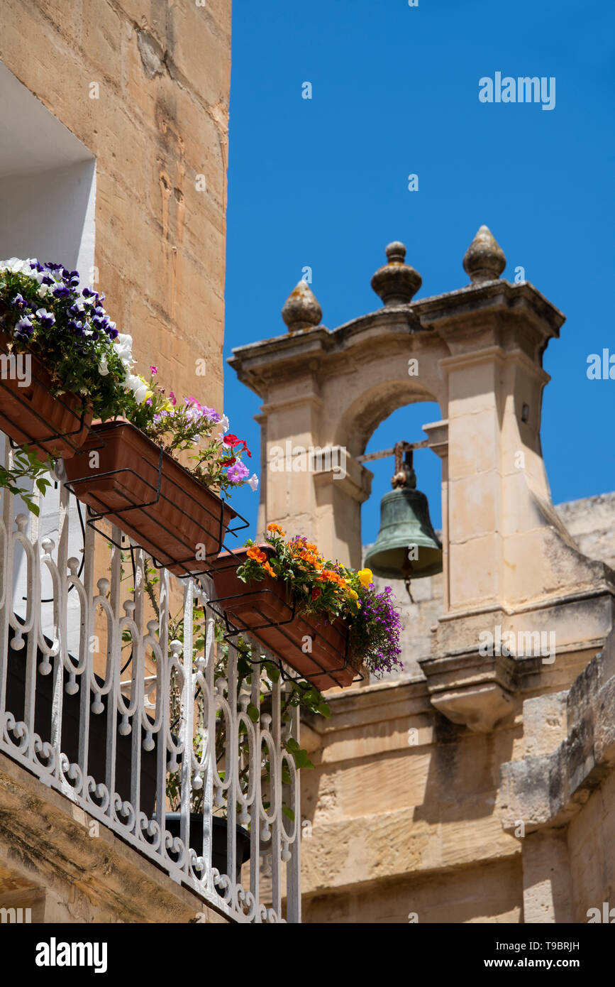 Europa, Malta, Mdina. Típica escena callejera con el antiguo campanario y cuadro de flores en el balcón. Foto de stock