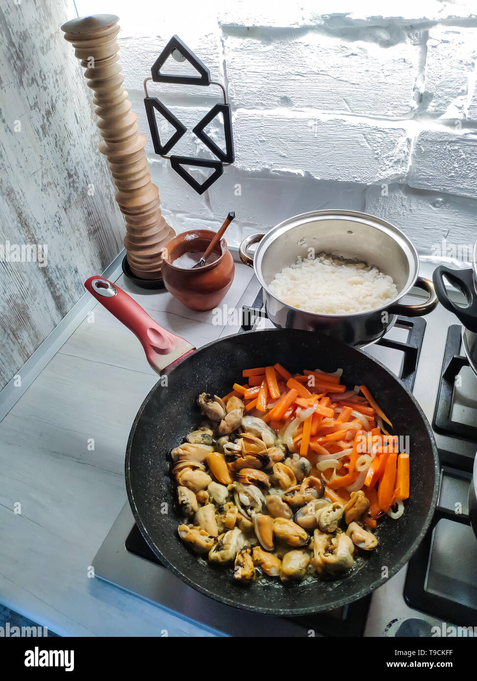 Marco encima de una cazuela con mejillones y verduras fritas en una cocina moderna. Foto de stock