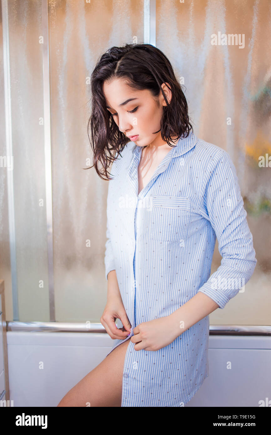Hermosa morenita mujer fija camiseta botones, el tiempo del baño. Niña  vestidos para arriba después de una ducha en casero ropa Fotografía de  stock - Alamy