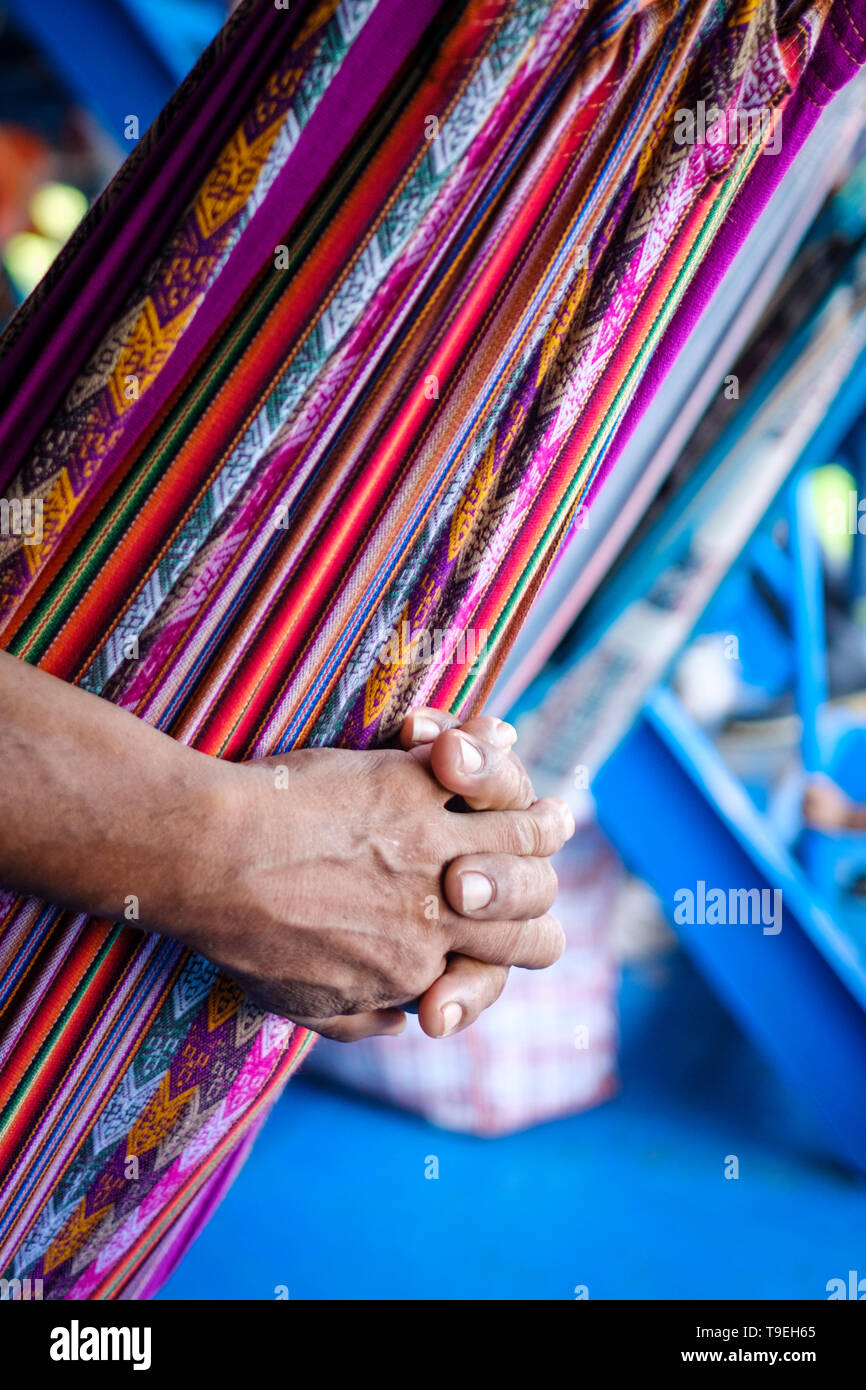 Detalle de un pasajero masculino manos mientras se relaja en una hamaca en la cubierta del ferry que va de Yurimaguas a Iquitos, región Loreto, Perú Foto de stock