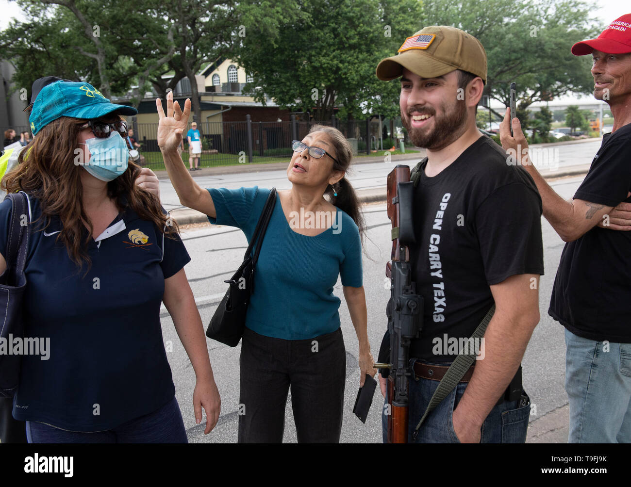 Un partidario de Ilhan Omar (centro) se enfrenta a los manifestantes antimusulmanes, alguna apertura portando armas legalmente, fuera de un hotel en Austin, Texas, donde el controvertido congresista musulmán habló en una cena Iftar celebrada en toda la ciudad. Foto de stock