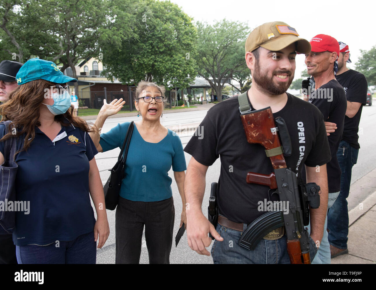 Un partidario de Ilhan Omar (centro) se enfrenta a los manifestantes antimusulmanes, alguna apertura portando armas legalmente, fuera de un hotel en Austin, Texas, donde el controvertido congresista musulmán habló en una cena Iftar celebrada en toda la ciudad. Foto de stock