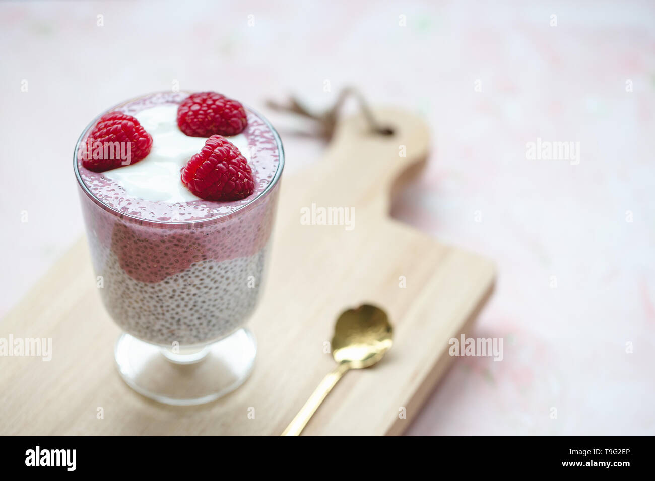 La semilla de chía parfait budín con leche de almendras, yogur, fruta del dragón de pitaya rosa polvo y frambuesas postre en un vaso. Súper alimento y comida vegana conce Foto de stock