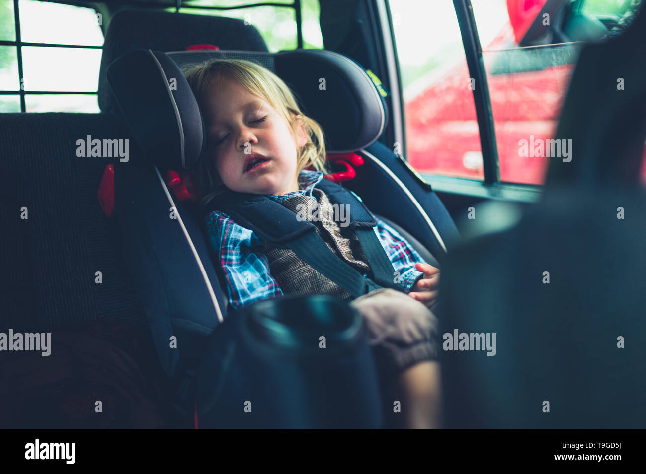 Un pequeño niño está durmiendo en el asiento para automóvil Foto de stock