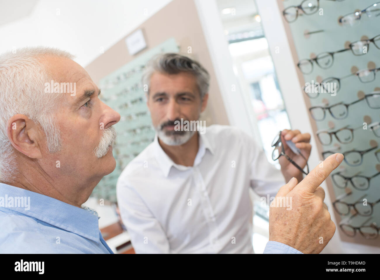 Hombre senior probando nuevas gafas sin reborde en el óptico Foto de stock