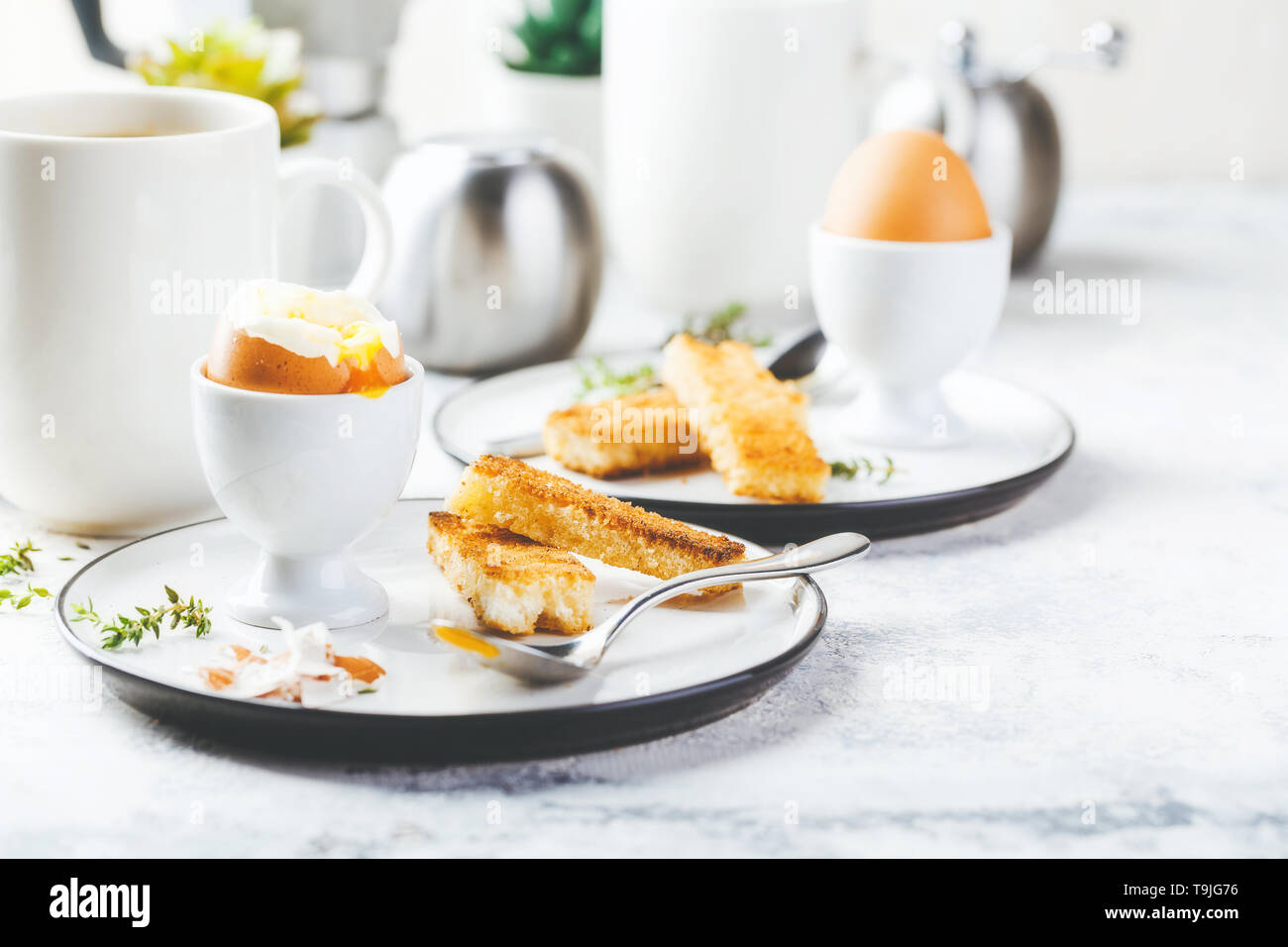 Huevo suave para el desayuno, con tostadas y café taza en segundo plano. Foto de stock