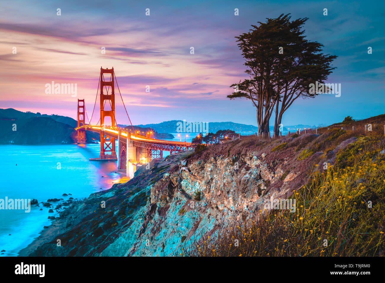 Classic vista panorámica del famoso Golden Gate Bridge visto desde la pintoresca playa de Baker en el crepúsculo del atardecer hermoso post con el cielo azul y las nubes al atardecer en Foto de stock