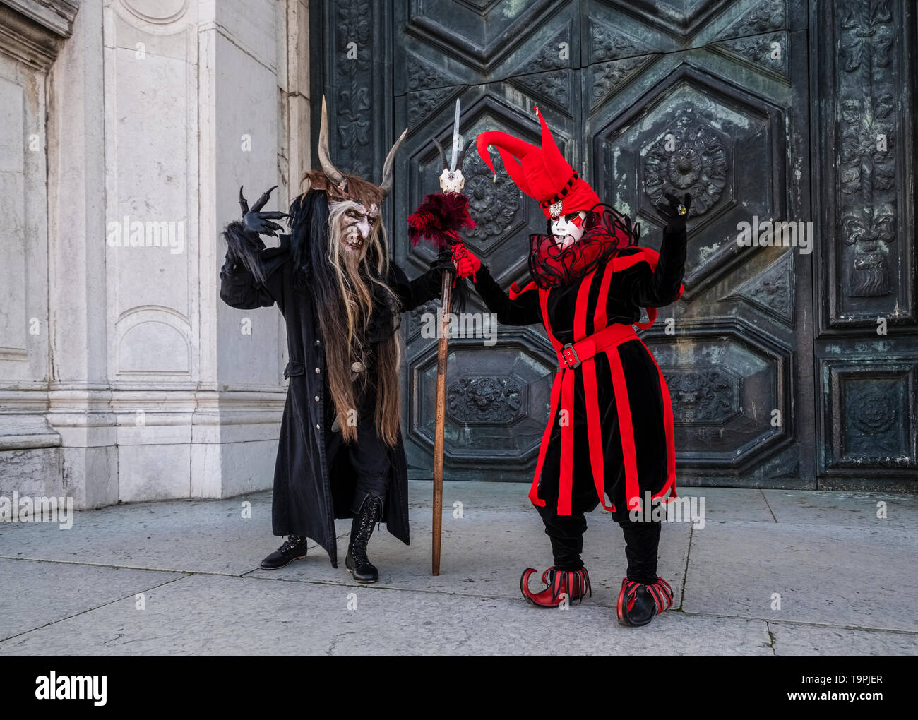 Una persona enmascarada en una espantosa creativos disfraces y otro en un  traje de Arlequín, celebrando el carnaval veneciano Fotografía de stock -  Alamy