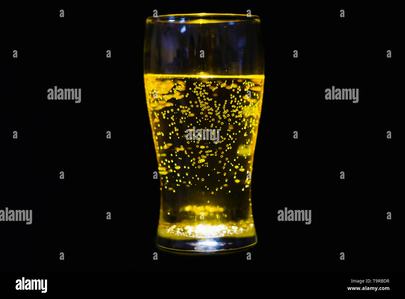 Refrescante copa con luz en el nadir saturando el interior del cristal y la soda con fondo negro crea una luz espectacular. Foto de stock