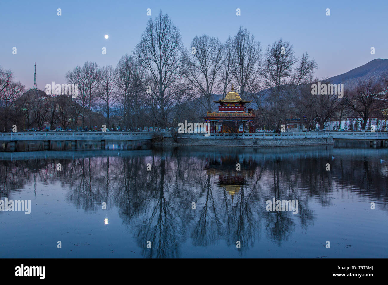 Una imagen del amanecer moonset sobre una pequeña pagoda en el lago en la Plaza del Potala en Lhasa, Tibet. Foto de stock