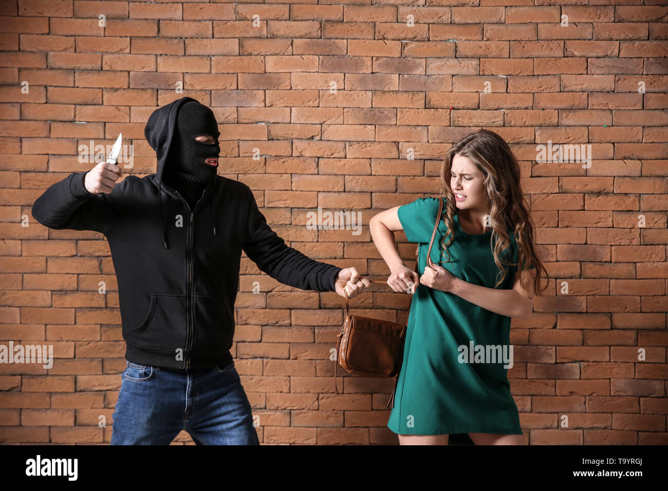 Macho ladrón robando bolsa desde joven contra la pared de ladrillo  Fotografía de stock - Alamy