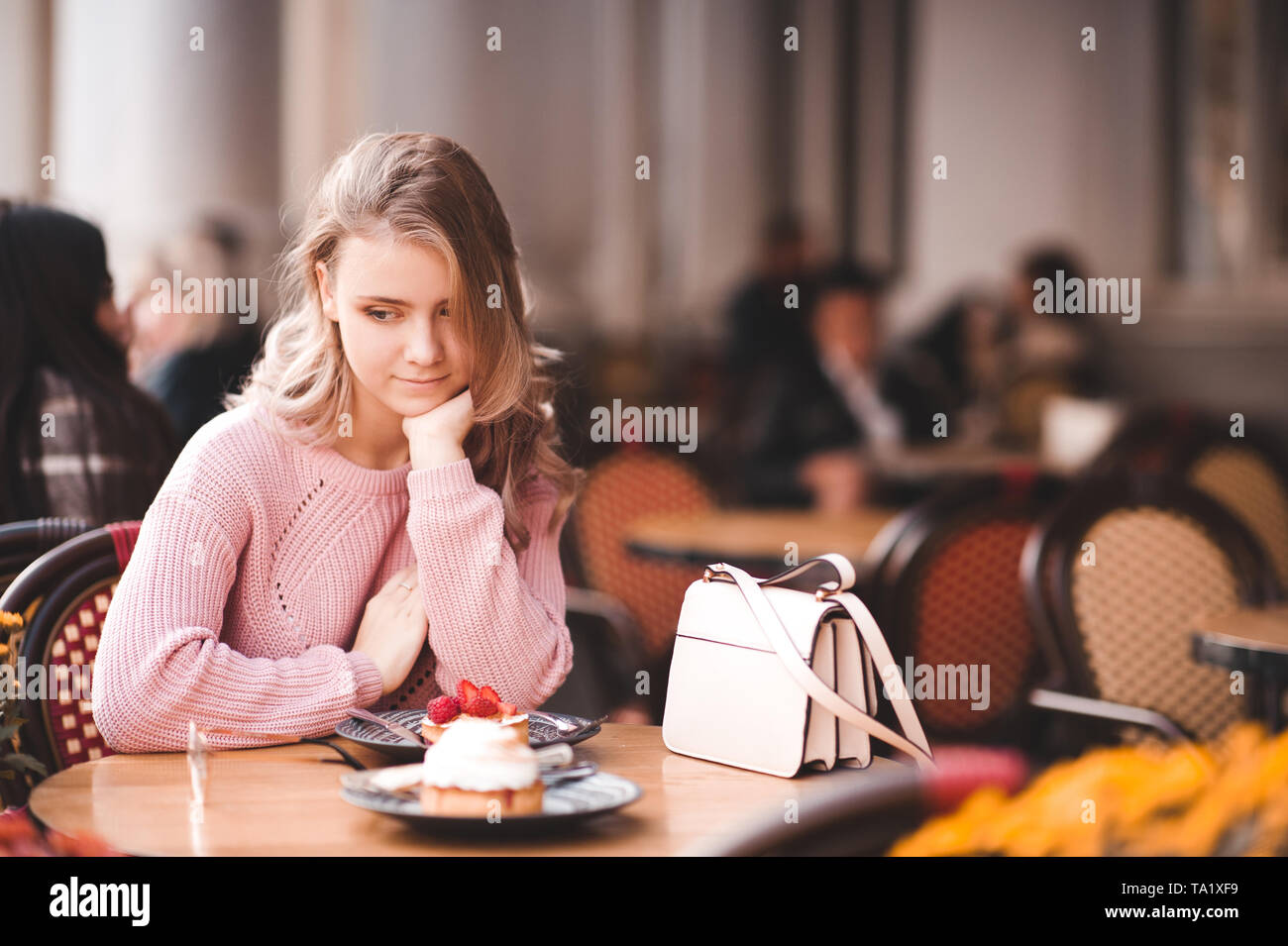 Jovencita rubia 16-17 años comiendo torta sentarse en cafeterías al aire libre. La temporada de verano. Foto de stock