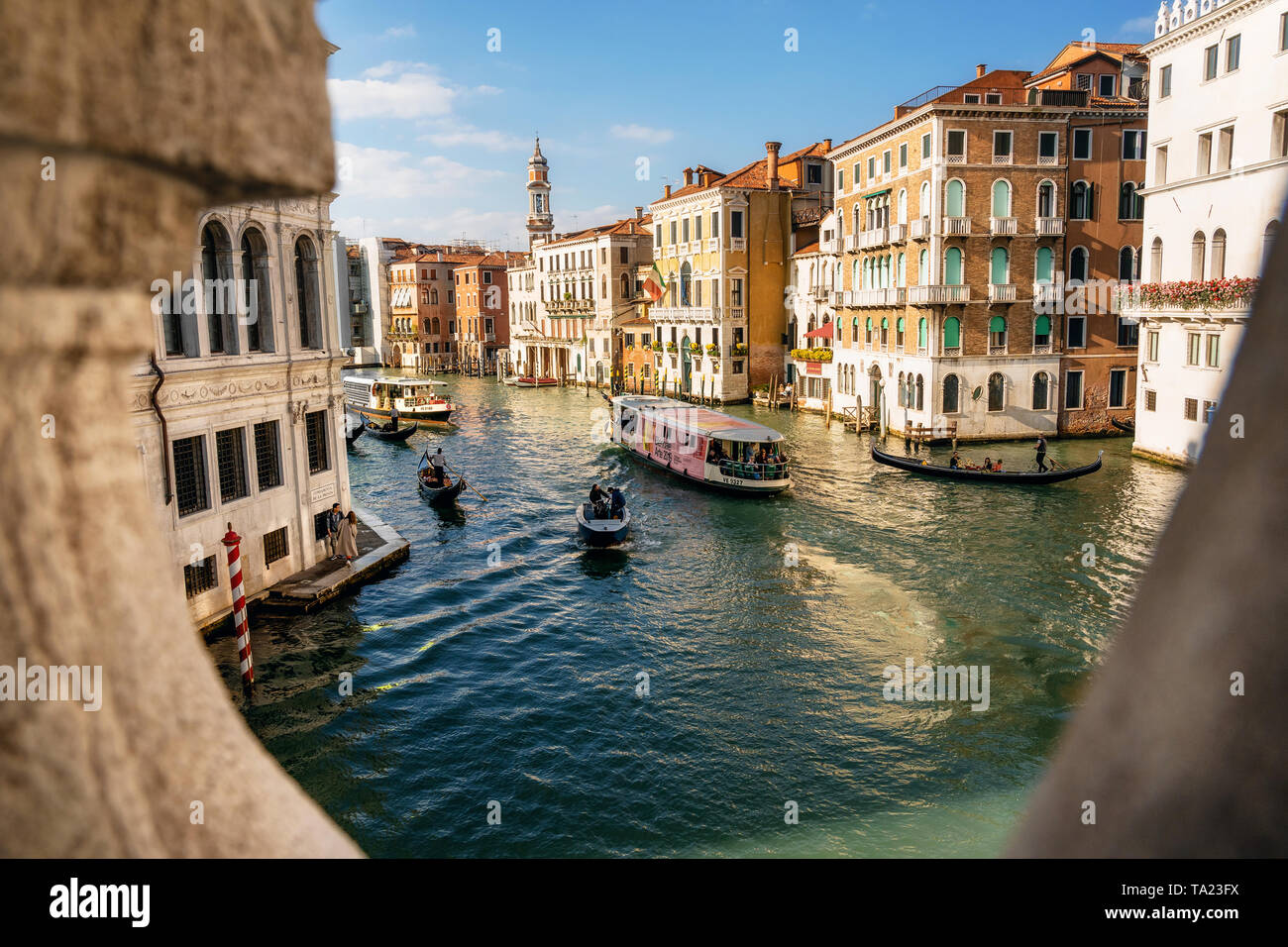 Las góndolas y los barcos flotan sobre el Gran Canal de Venecia, Italia. Vista a través de la baranda del Puente Rialto Foto de stock