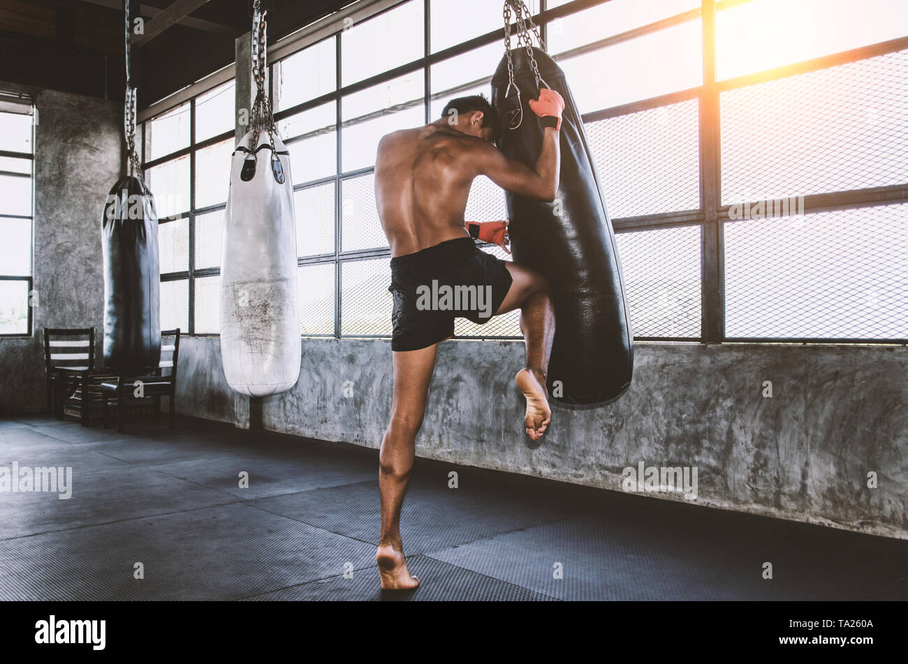 Luchador de muay thai entrenando en el gimnasio con el punch bag Foto de stock