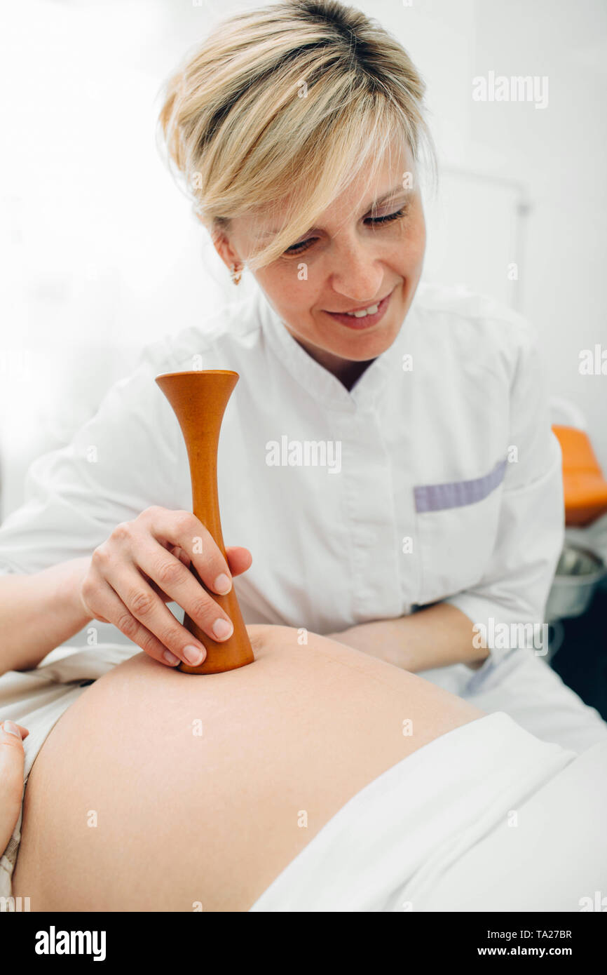 Mujer embarazada tras examen por su obstetra. Doctora escuchando embarazada vientre con equipo médico especial Foto de stock