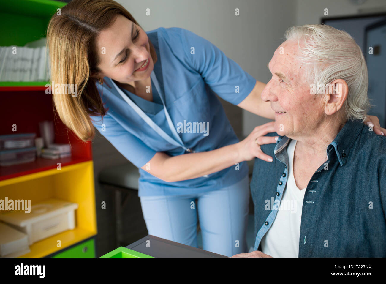 Cuidador feliz ayudando al hombre superior. Apoyar la enfermera amable anciano con la enfermedad de Parkinson Foto de stock